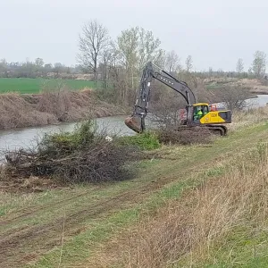 Excavator clearing brush and snagging debris from the ditch bank at the start of the work