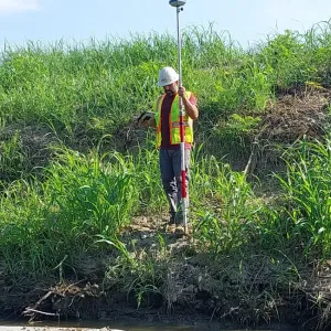 RKE crew member taking survey shots along the excavated bank with a GPS rover