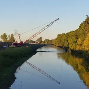 Dragline working the channel at sunset along a cleaned reach