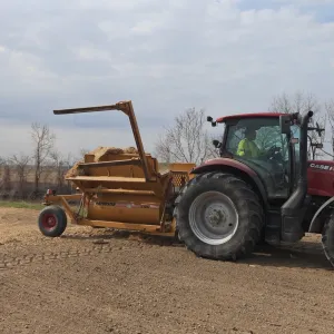 Tractor and mulch spreader placing straw across the restored top bank