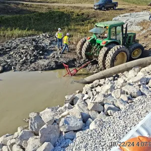 Crew setting the unwatering discharge line alongside the completed riprap cofferdam