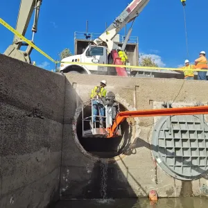 Boom-lift work inside the center culvert barrel as the next flap gate is rigged overhead