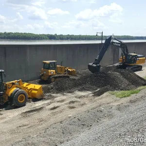 Wheel loader, dozer and excavator spreading and shaping crushed rock along the base of the floodwall
