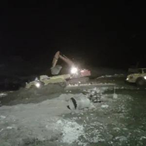 Night work under floodlights, with an excavator loading an articulated dump truck