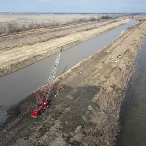 Dragline and excavator working from the bank, with freshly cast spoil shaped along the top bank