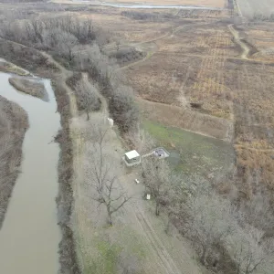 Aerial of a wooded reach past an existing gauge structure on the channel bank