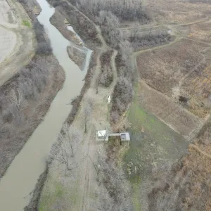 Aerial of a wooded reach at an existing water-control structure below the cleared field edge