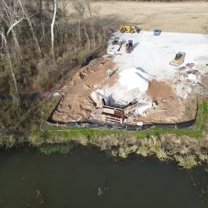 Aerial of the opposing abutment under construction, with backfill placed and equipment staged on the access pad