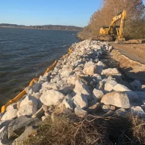 Riprap bank protection being placed along the reservoir shoreline behind a floating turbidity barrier