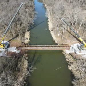 Aerial of the two cranes positioned on opposite banks of the slough during the lift