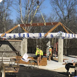 Crane setting the prefabricated timber roof assembly onto the committal shelter columns