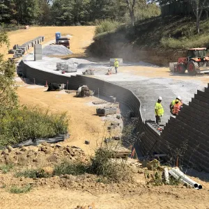 MSE wall rising through the cut as backfill is placed and compacted in lifts
